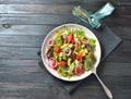 Fresh avocado salad with cherry tomatoes, red onion, arugula beet leaves, yellow sweet pepper on the black wooden background.