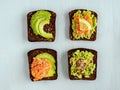 Fresh avocado toasts with different toppings on light blue wooden background. Healthy vegetarian breakfast with rye Royalty Free Stock Photo