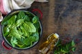 Fresh baby spinach leaves in a bowl and olive oil on a wooden table. Top view.