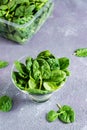 Fresh baby spinach leaves in a glass bowl and behind on a texture table. Vertical view. Close-up Royalty Free Stock Photo