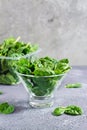 Fresh baby spinach leaves in a glass bowl and behind on a texture table. Vertical view Royalty Free Stock Photo