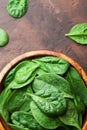 Fresh baby spinach leaves in wooden bowl on rustic stone table top view. Organic healthy food. Royalty Free Stock Photo