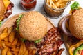 Fresh bacon burgers and fries on white wooden table, above view Royalty Free Stock Photo
