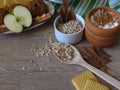 Fresh and baked apples, shortbread biscuits, oats in an wooden spoon, yogurt and cinnamon sticks on rustic style oak background.