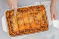 Fresh baked beef lasagna in baking dish close up on kitchen table. Woman cuts lasagna Royalty Free Stock Photo