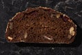 Fresh baked black bread slice with nuts on stone black surface Royalty Free Stock Photo