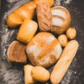 Fresh baked bread with a golden crust, loaf, buns, white, rye on a rustic wooden background with sil rustic. Flat layout