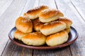 Fresh baked buns sprinkled with sesame seeds in a plate on a wooden table Royalty Free Stock Photo