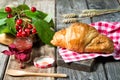 Fresh baked croissant with cherries and jam, wooden background Royalty Free Stock Photo