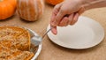 Fresh baked homemade pumpkin pie decorated with crushed nuts and orange zest. Woman hands serving pie on a plate Royalty Free Stock Photo