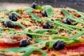 Fresh baked hot pizza on the black background close up. Vegetarian pizza with vegetables, black olives and rucola Royalty Free Stock Photo