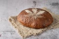 Fresh baked loaf of spelt sourdough bread with crushed hemp seeds is decorated with cannabis leaf made of flour on linen towel on Royalty Free Stock Photo