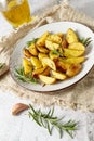 Fresh baked potatoes with olive oil, rosemary and garlic on vintage plate closeup over beige linen towel Royalty Free Stock Photo