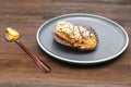 fresh baked sweet creamy eclair sweet dessert on plate with spoon, kitchen wooden table, sugar food, utensils dishware