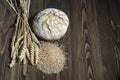 Fresh baked wheat bread loaf, a handful of wheat grain and wheat ears on a dark brown wooden background. Royalty Free Stock Photo