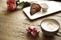 Fresh bakery croissant, coffee with heart sign, rose flowers on wooden table. Romantic breakfast for Valentine`s Day celebrate con Royalty Free Stock Photo