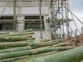 Fresh bamboo poles are placed close to the constructing house, ready to be used for scaffold installation around the constructing Royalty Free Stock Photo