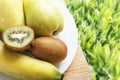 Fresh banana, pear and kiwi for healthy dietary breakfast on wooden table and on green grasses background. Natural organic ripe fr Royalty Free Stock Photo