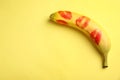 Fresh banana with red lipstick marks on yellow background. Oral sex concept