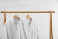 Fresh bathrobes hanging on rack near wall Royalty Free Stock Photo