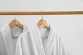 Fresh bathrobes hanging on rack near wall Royalty Free Stock Photo