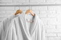 Fresh bathrobes hanging on rack near white wall Royalty Free Stock Photo