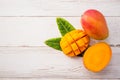 Fresh and beautiful mango fruit with sliced diced mango chunks on a light wooden background, copy spacetext space