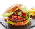 Fresh Beef Burger with Bacon, Fried Onions, Tomato Sauce, Pickled Cucumbers, Green Lettuce, Cheese and French Fries Garnish. Hambu Royalty Free Stock Photo