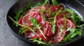 Fresh beef carpaccio with arugula and parmesan on a dark plate