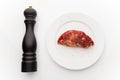 Fresh beef meat on white plate and black pepper mill Royalty Free Stock Photo