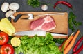 Fresh beef steak, wooden spoon, Assortment of Fresh Vegetables, aromatic herbs, spices and vegetables for cooking , on black  back Royalty Free Stock Photo