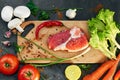 Fresh beef steak, wooden spoon, Assortment of Fresh Vegetables, aromatic herbs, spices and vegetables for cooking Royalty Free Stock Photo