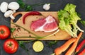 Fresh beef steak, wooden spoon, Assortment of Fresh Vegetables, aromatic herbs, spices and vegetables for cooking Royalty Free Stock Photo