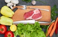 Fresh beef steak, wooden spoon, knife and Assortment of Fresh Vegetables, aromatic herbs, spices and vegetables for cooking Royalty Free Stock Photo