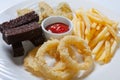 Fresh beer snacks assortment on a white plate. French fries, croutons and zucchini and onion rings. Royalty Free Stock Photo