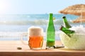 Fresh beers on table on beach with straw umbrellas