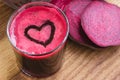 Fresh beet juice in glass, heart shape foam and sliced beetroot on wooden table. Royalty Free Stock Photo