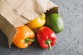 Fresh bell peppers of different colors and green avocado delivered in brown paper bag Royalty Free Stock Photo