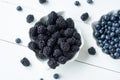 Fresh berries of blackberries  blueberries  mint leaves  in white bowl and blue mug on wooden background. Top view. Copy space Royalty Free Stock Photo