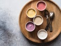 Fresh berries ice cream of different colors in paper cups and metal spoons on round wood tray on a gray background. Top view. copy Royalty Free Stock Photo