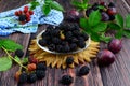 Fresh berries and leaves of blackberries and purple ripe plums on a brown wooden background.