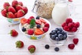 Fresh berries strawberry, raspberries and natural flakes for breakfast, Woman pouring milk into bowl with muesli top Royalty Free Stock Photo