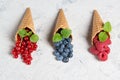Fresh berries in waffle cones on stone background, raspberry, blueberry and redcurrant with mint leaves Royalty Free Stock Photo