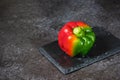 Fresh bicolor red and green bell pepper with water droplets on black concrete background Royalty Free Stock Photo