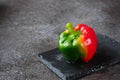 Fresh bicolor red and green bell pepper with water droplets on black concrete background Royalty Free Stock Photo