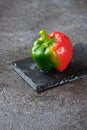 Fresh bicolor red and green bell pepper with water droplets on black concrete background Royalty Free Stock Photo