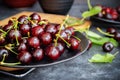 Fresh black cherry on grey ceramic plate on wooden cutting board and green leaves on dark background. Close-up. Dark low key photo Royalty Free Stock Photo