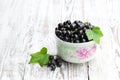 Fresh black currant in ceramic bowl on white wooden table Royalty Free Stock Photo