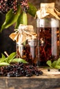 Fresh black elderberry syrup in a glass bottle on a wooden table. Vertical Royalty Free Stock Photo