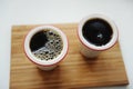 Fresh black filter coffee in two ceramic cups without handle on bamboo tray. White background. Top view, close up Royalty Free Stock Photo